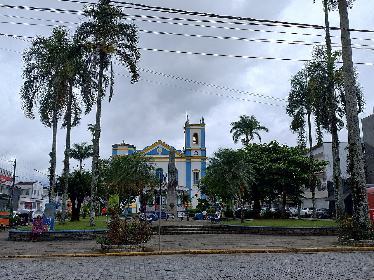 Igreja Matriz de Ubatuba e o cruzeiro na praça central, entre palmeiras.